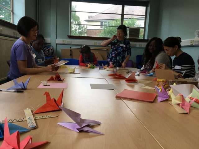 Shelanu members are making origami cranes with the ASIRT kids