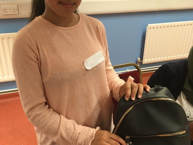 Refugee Action client proudly showing their finished fabric keyring on bag
