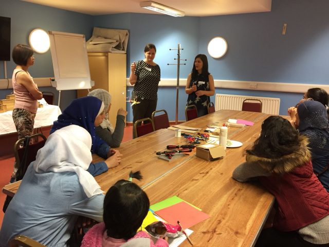 Craftspace staff member and Shelanu talking to Refugee Action clients about Shelanu projects