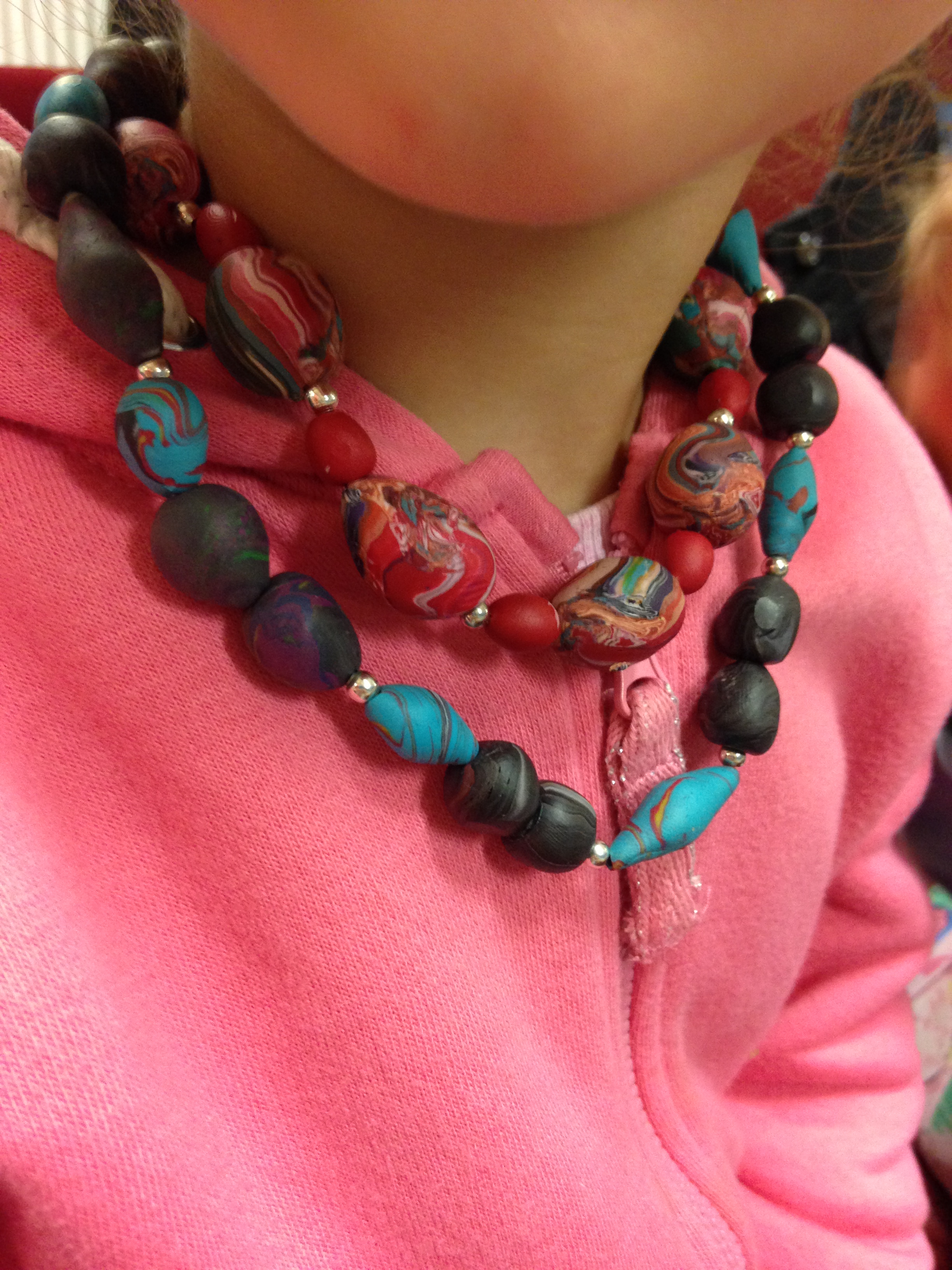 A child is fitting her beautiful polymer clay jewellery pieces