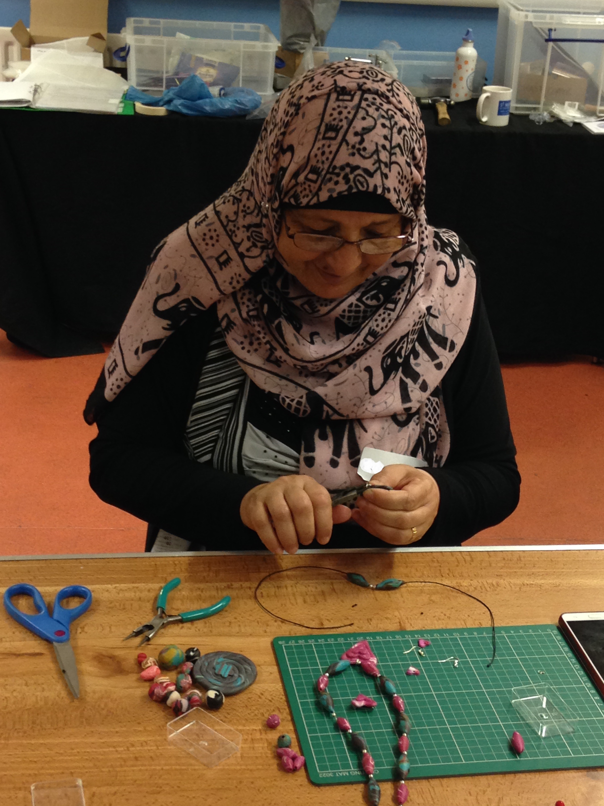 Refugee Action client bends the pearl eyelet for her nacklace.