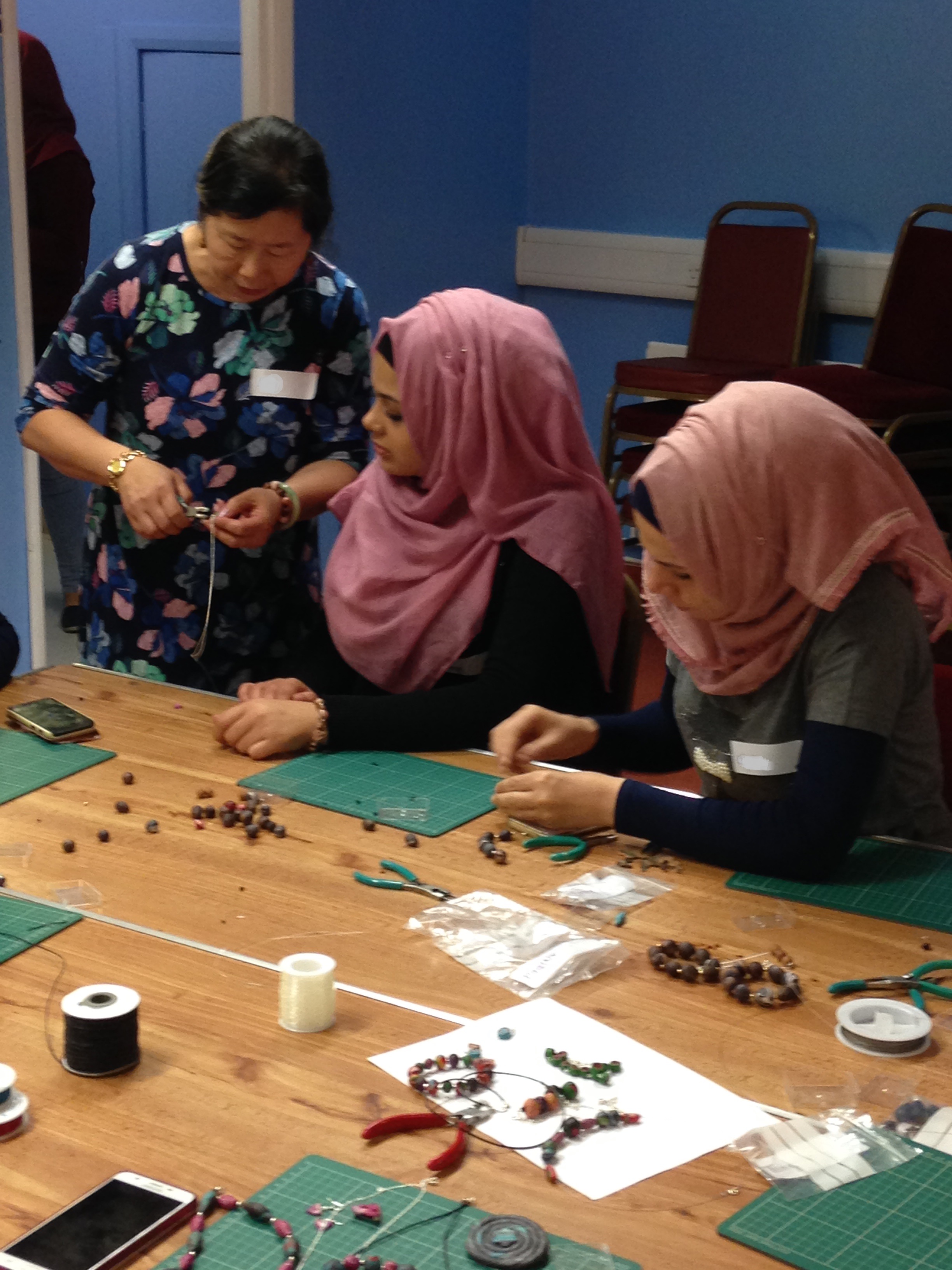 Shelanu member helps Refugee Action client to finish polymer clay jewellery