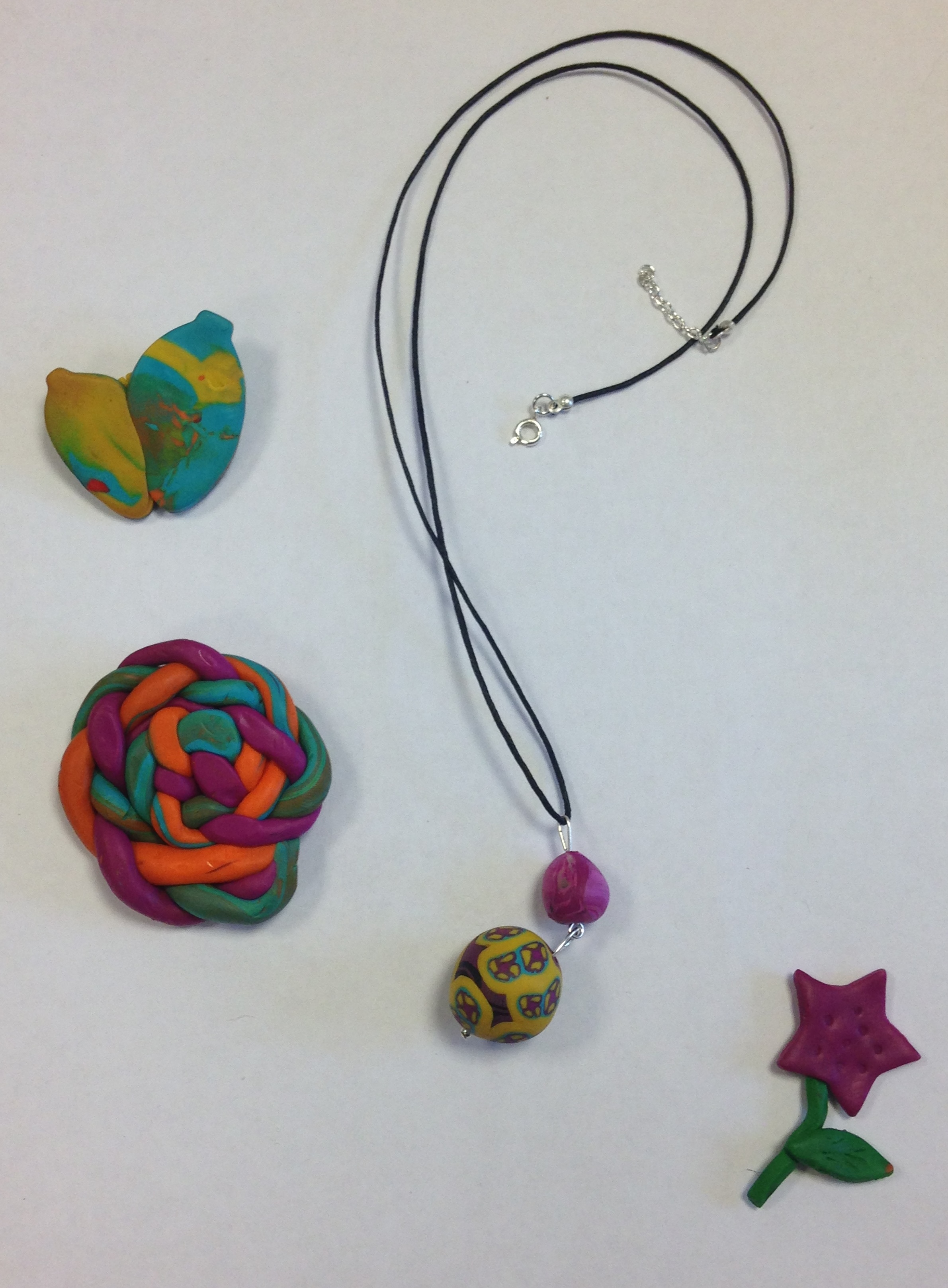 a flower, necklace and two other colorful pieces of clay