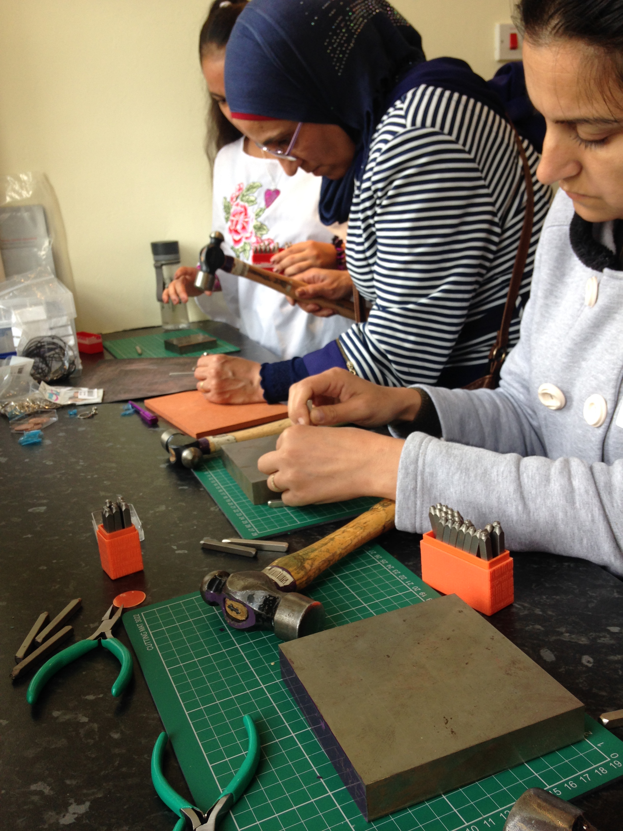The women are trying out stamping on copper.